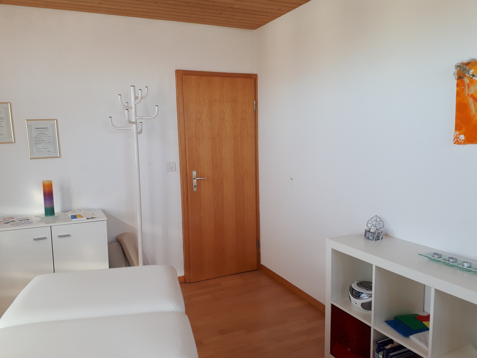 Blick in den Praxisraum mit Regal und Garderobe